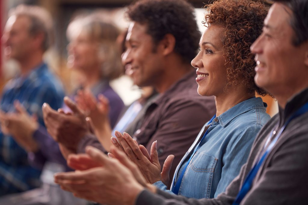 Group Of Casually Dressed Businessmen And Businesswomen Applauding Presentation At Conference