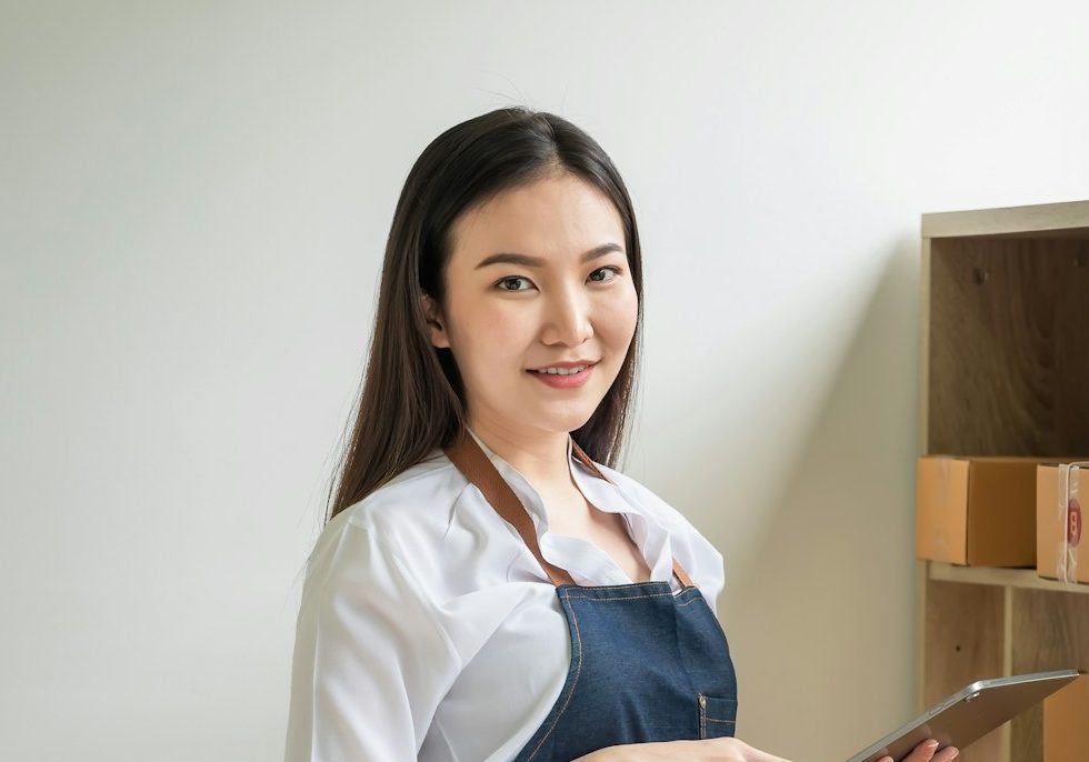 Asian woman small business owner holding a tablet to check parcels before delivering to customer